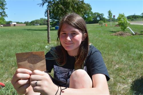 girl smiles and holds a message of a slip of biodegradable paper